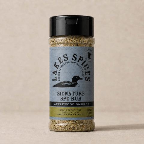 A 6oz bottle of Lake Spices Applewood Smoked Signature SPG Rub, featuring the company logo of a black loon on a blue-grey background, and a black icon of Minnesota in the upper righthand corner. Label text above the loon reads “Lake Spices: Honest Blends for Homemade Taste.”

Ingredients: salt, pepper, and garlic with a subtle smoky flavor