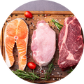 Three raw meat cuts arranged on a wooden board: a salmon fillet slice on the left, a pink pork cut in the center, and a red beef steak on the right, with spices, herbs, and cherry tomatoes.